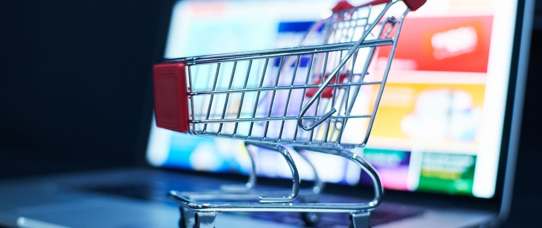 Small shopping cart placed on a laptop keyboard, representing online shopping and e-commerce concepts.