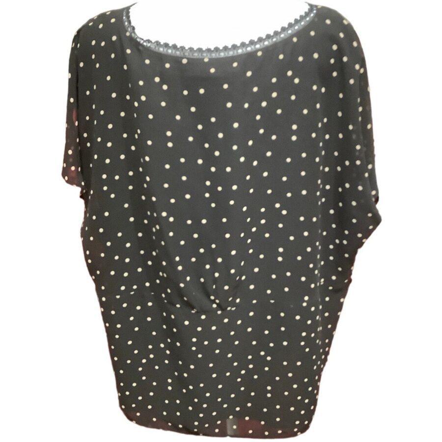 A black, short-sleeve, polka dot blouse with small, white dots and a lace-trimmed neckline is displayed against a plain background.