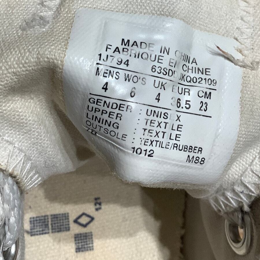 A close-up of a shoe tag showing size information, material composition, and manufacturing details. The shoe is labeled as unisex and made in China.