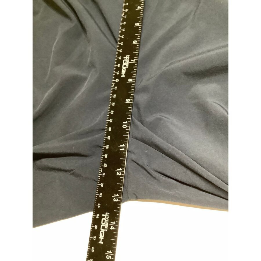 A black fabric is measured with a 16-inch ruler placed diagonally across it. Creases are visible in the fabric's surface.