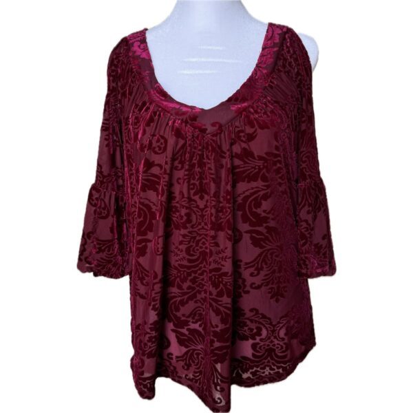 A burgundy velvet top with an intricate floral pattern is displayed on a mannequin with three-quarter sleeves and a scooped neckline.