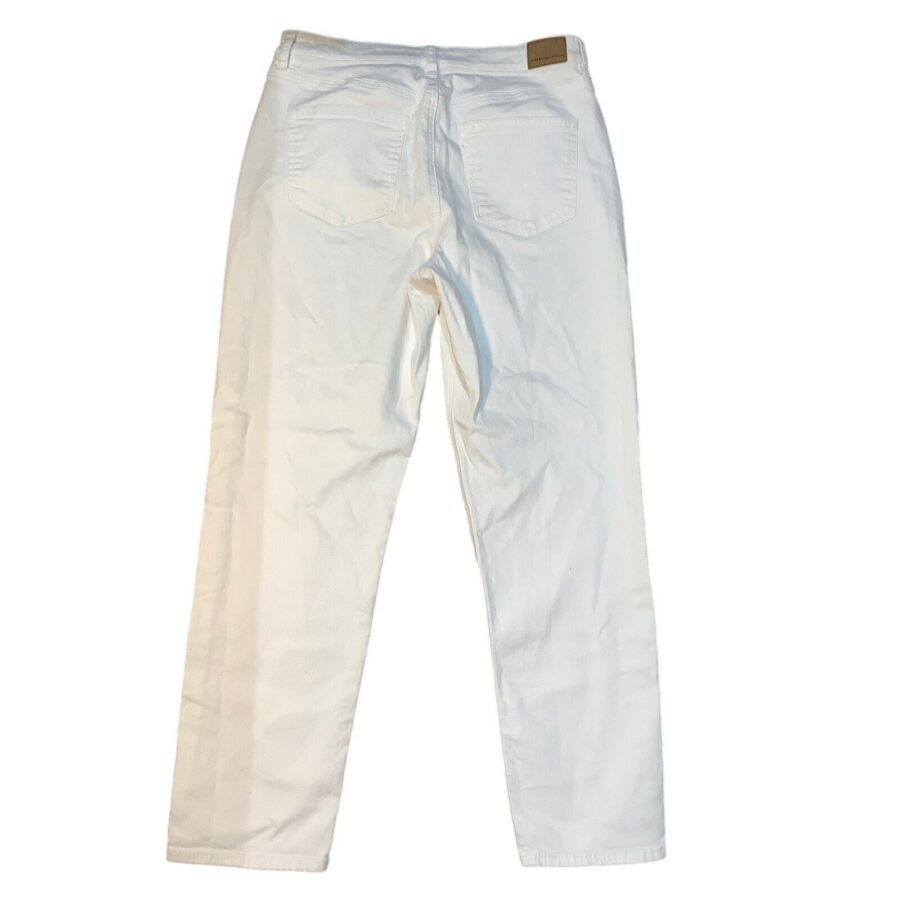 A pair of white jeans is laid flat with back pockets and a visible brown tag on the waistband.