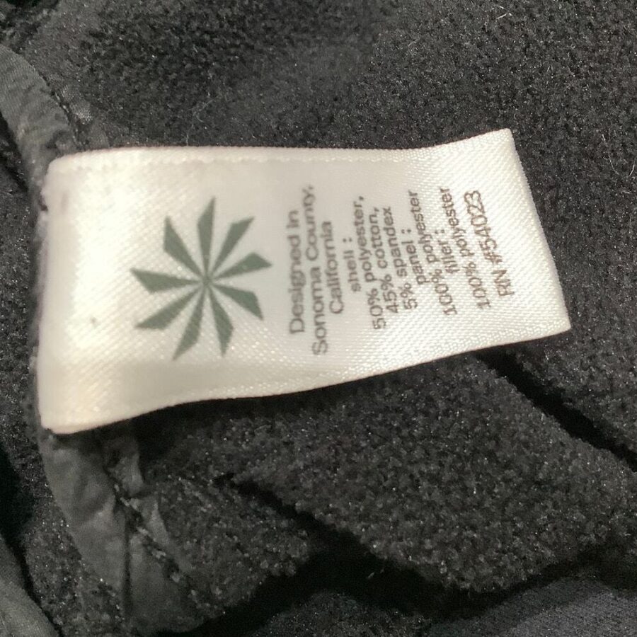 A clothing label displays material information and manufacturing details, including "Designed in Sonoma County, California," attached to a dark fabric.