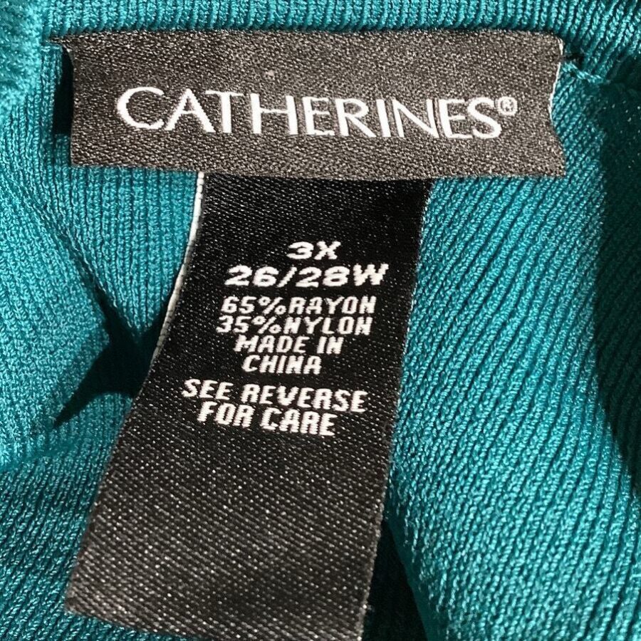 A clothing label with 'Catherines', size 3X 26/28W, 65% rayon, 35% nylon, made in China. Text advises to see reverse for care instructions.