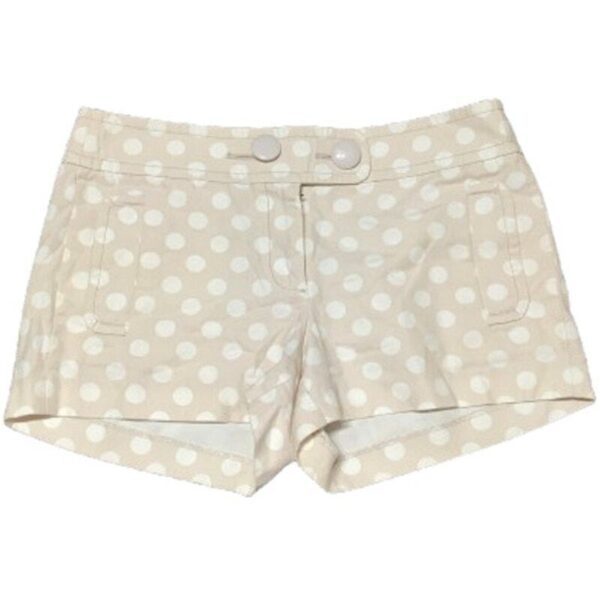 The image shows beige shorts with white polka dots, two front pockets, and a double button closure at the front waistband.