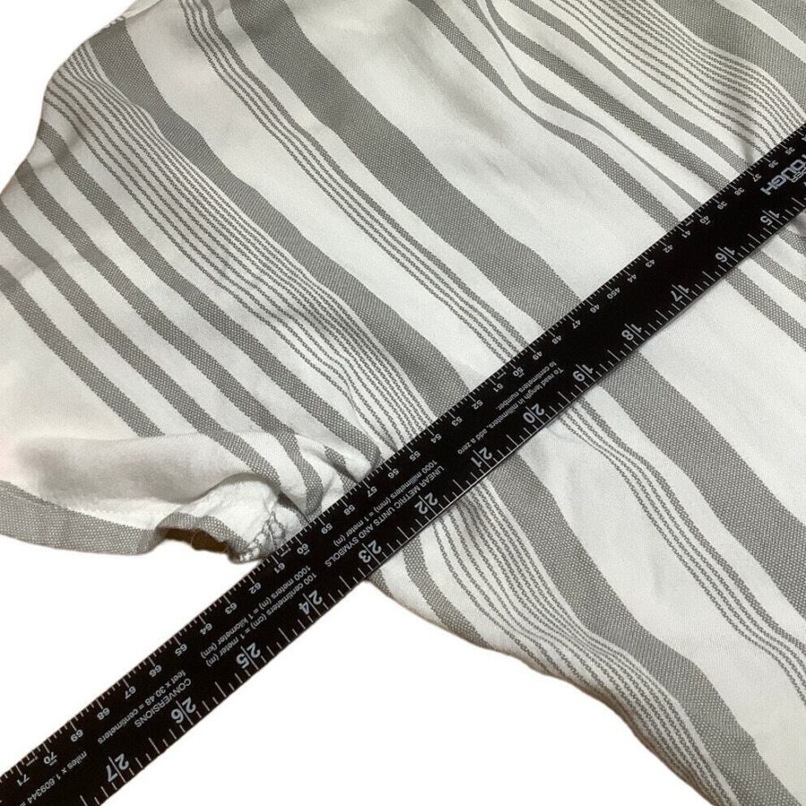 A fabric with gray and white stripes is being measured with a black ruler, showing dimensions in both inches and centimeters.