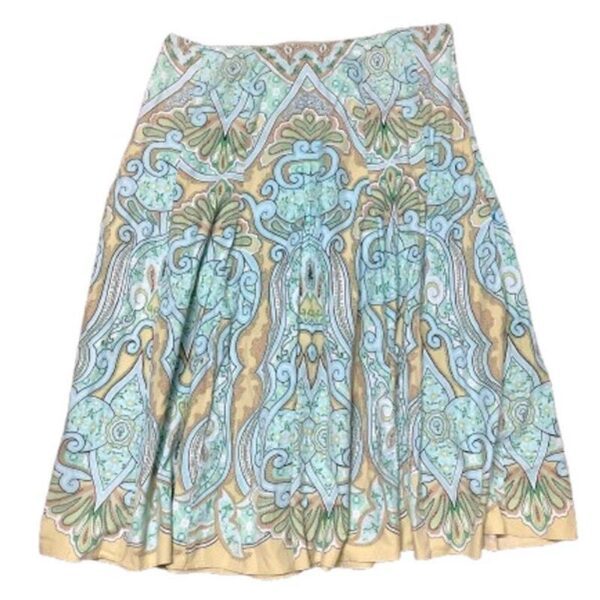 A colorful knee-length skirt features intricate, symmetrical patterns in shades of green, blue, and beige, showcasing detailed floral and geometric designs.