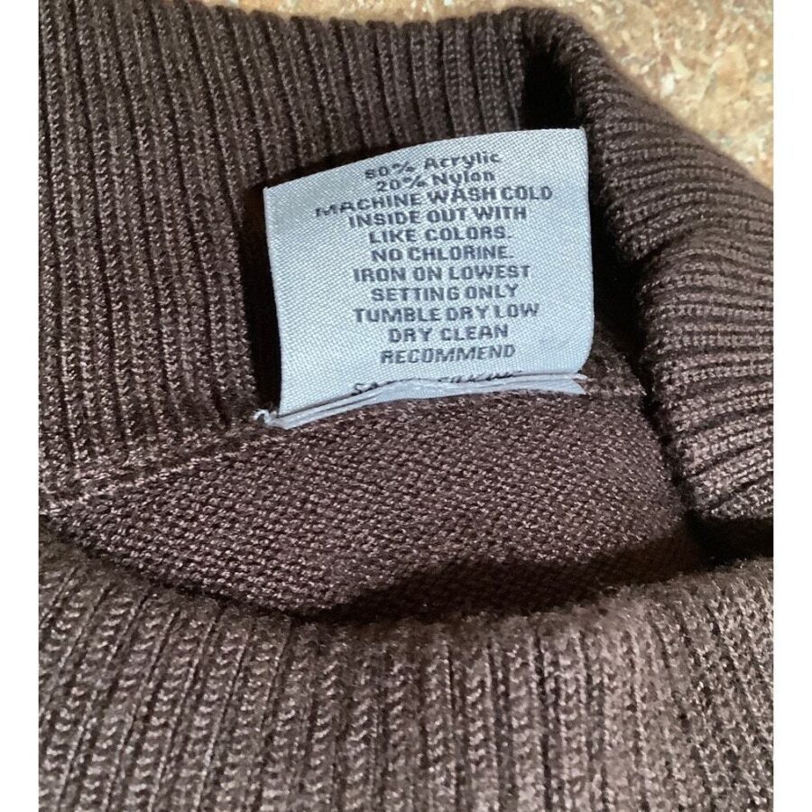 This image shows a brown sweater with a care label. The label provides washing instructions, recommending machine wash cold and dry cleaning.