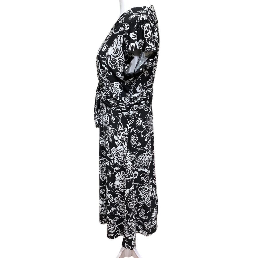 The image shows a black and white floral dress on a mannequin, displayed in a side profile view. No landmarks or historical buildings are present.