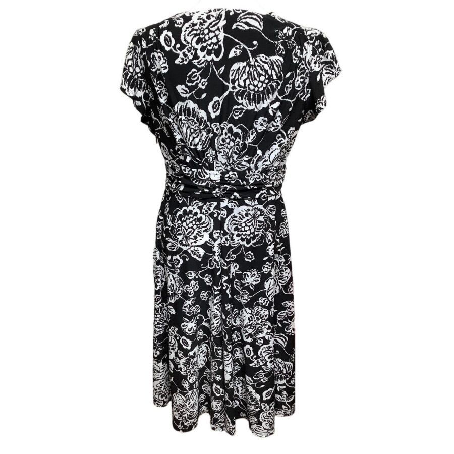 This image shows a black dress with white floral patterns, seen from the back. The dress has short sleeves and a knee-length design.