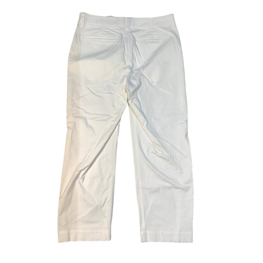 A pair of white pants lies flat with visible creases and minimal detailing, showcasing a simple, casual design. There are no landmarks or buildings present.