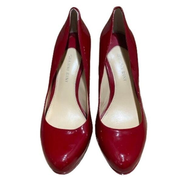 A pair of shiny, red high-heeled shoes with a pointed toe design, brand "Gianni Bini" inscribed on the insole.