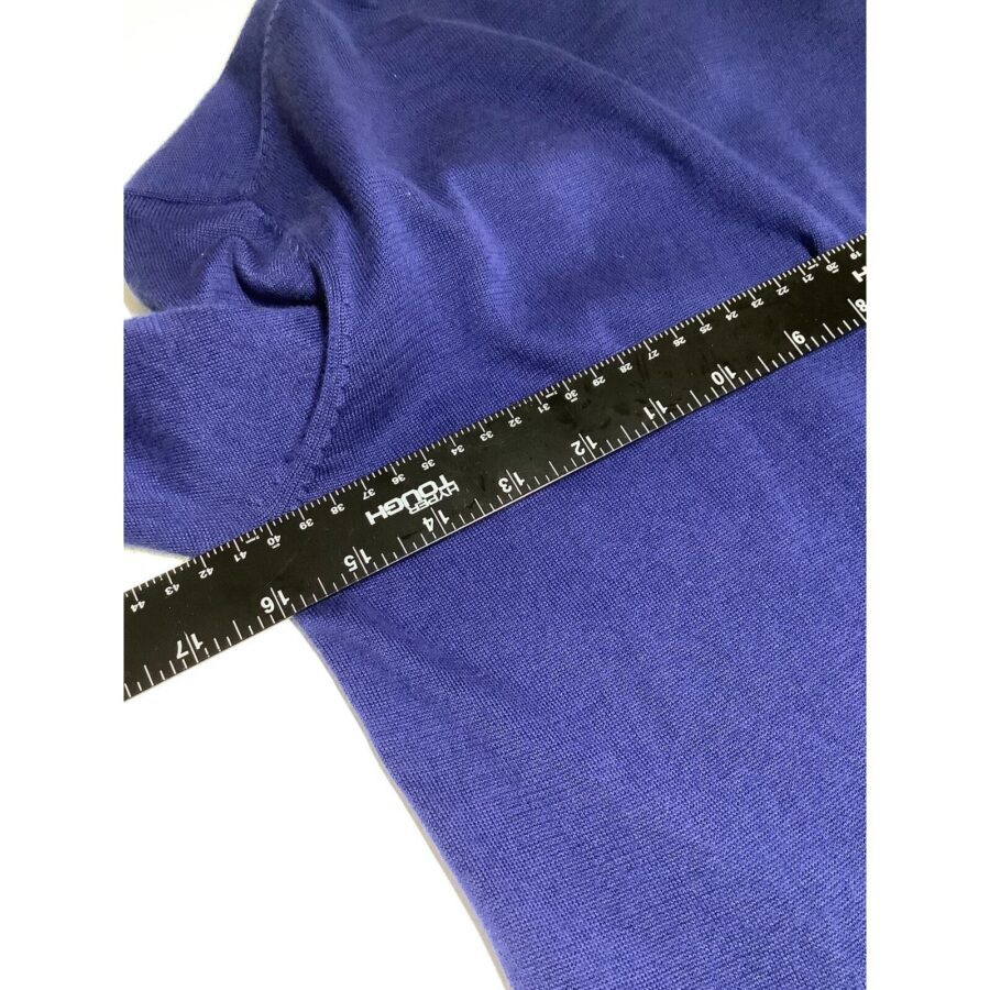 A black ruler measures a royal blue fabric laid flat, likely a garment or cloth. The background is plain white. No landmarks present.