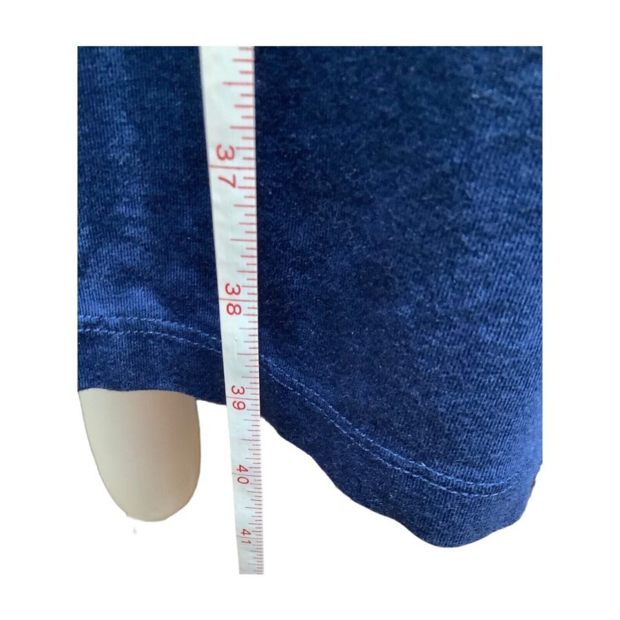 A blue fabric is being measured with a white measuring tape, showing approximately 39 centimeters. The fabric appears to be a garment.