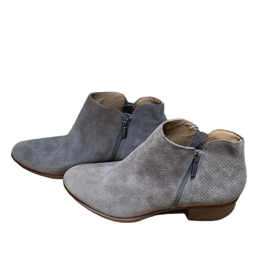 A pair of gray suede ankle boots with side zippers is placed against a white backdrop. The boots are stylish and casual.