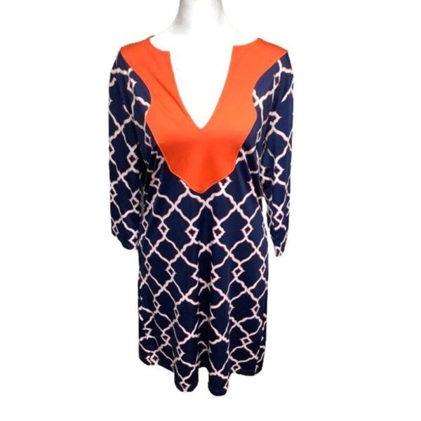 A mannequin wearing a dress featuring a bold, geometric blue and white pattern with a striking orange "V" design at the neckline and chest.