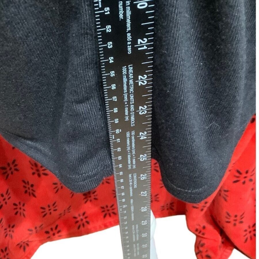 A person is measuring a black and red piece of fabric with a ruler, capturing measurements up to 27 inches.