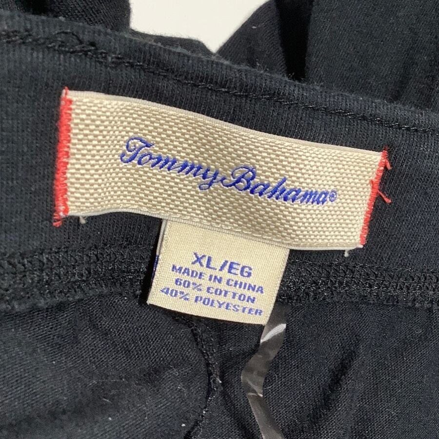 A beige garment label with "Tommy Bahama" and size XL/EG text on black fabric, detailing fabric composition and manufacturing origin.