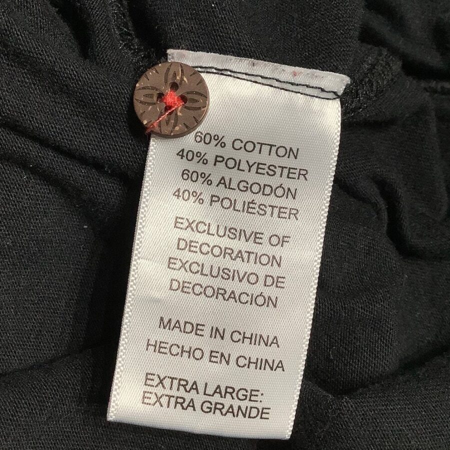 A clothing tag detailing fabric composition and care instructions is attached to black fabric with a button. No landmarks or historical buildings are visible.