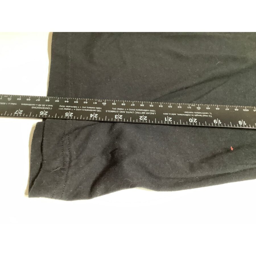 A black fabric with a white-on-black ruler showing measurements is laid flat for scale against the fabric. No landmarks or historical buildings present.