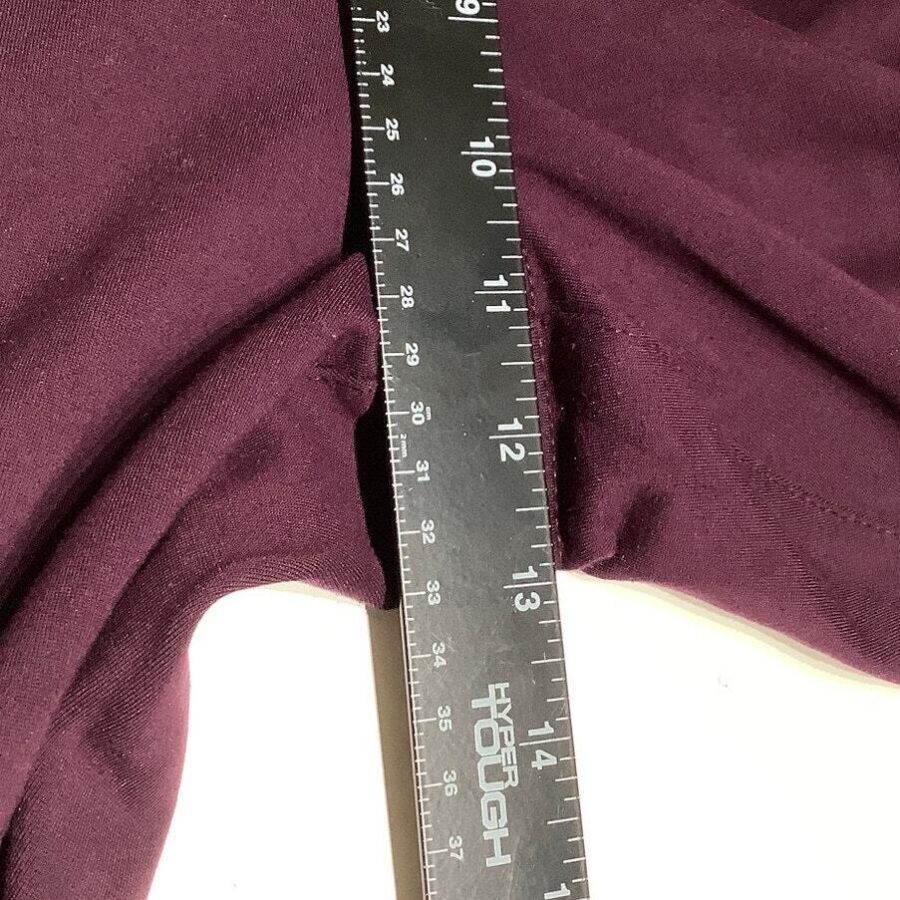 A black ruler measuring a piece of dark purple fabric, showing measurements in inches and centimeters, placed on a white surface.