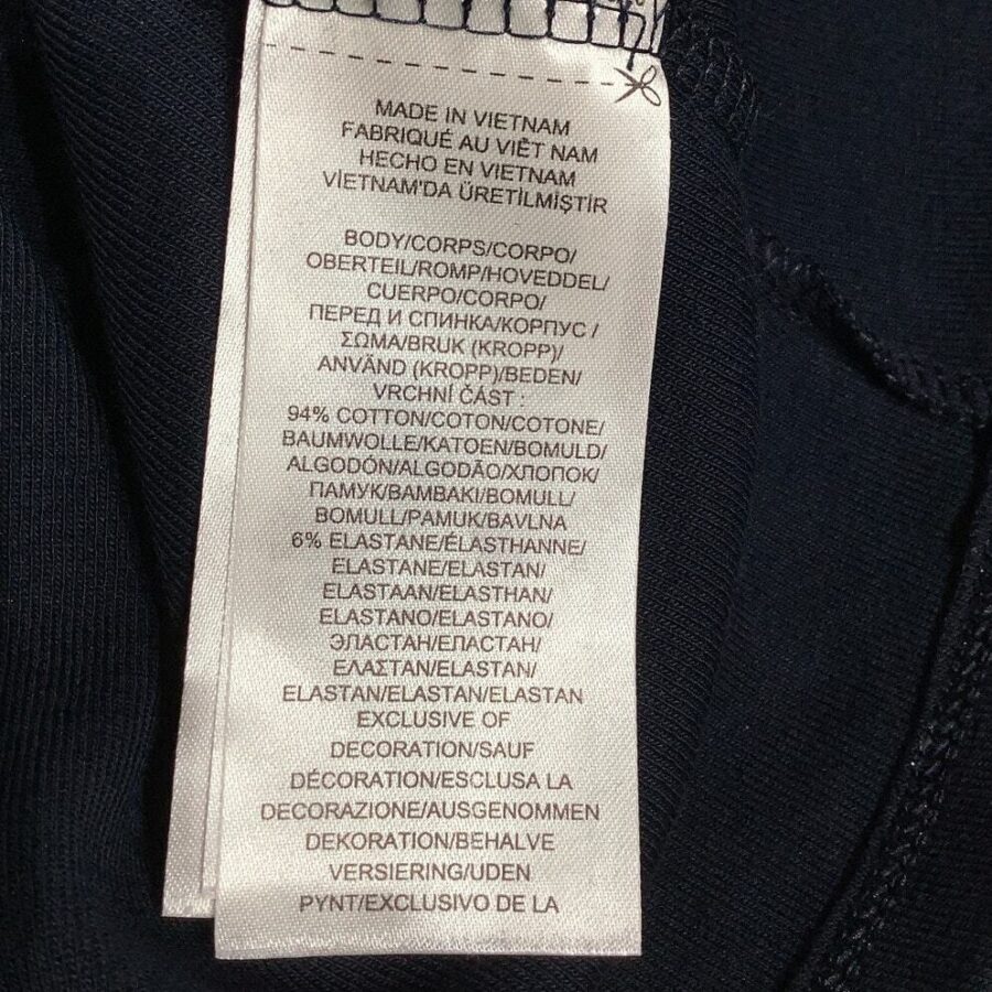 A clothing tag indicating it was made in Vietnam. It lists materials in multiple languages, including cotton and elastane, and mentions exclusive decorations.