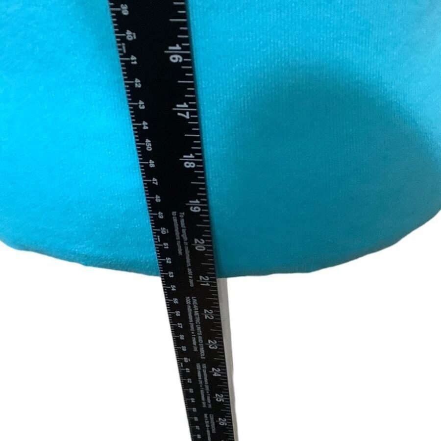 A black ruler measures the height of a turquoise object, which appears to be soft and rounded in texture. No landmarks or buildings visible.