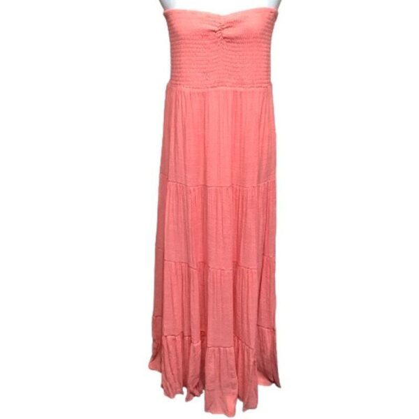 A strapless, coral maxi dress with a ruched bodice and tiered skirt. The dress features a lightweight, flowy fabric ideal for summer wear.