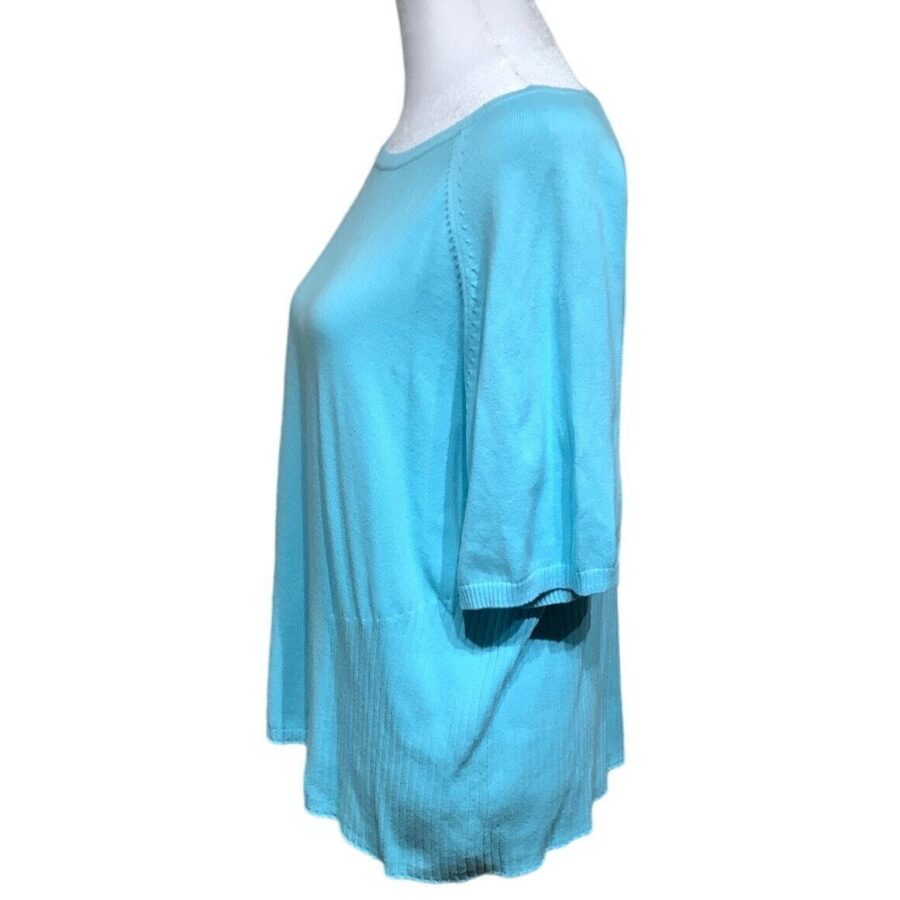 A blue short-sleeved shirt is displayed on a dress form in a side view, highlighting the garment's relaxed fit and fabric texture.