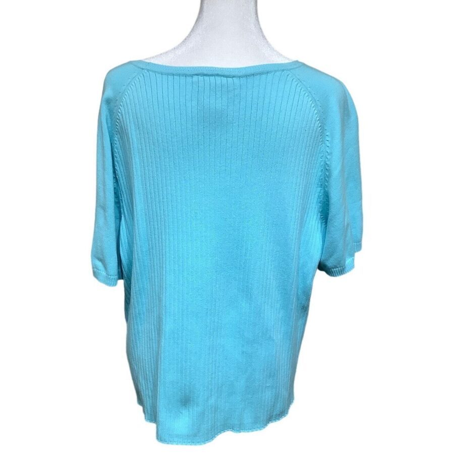 A light blue, short-sleeved sweater is displayed on a headless mannequin. The sweater features ribbed knitting details around the shoulders and upper back.