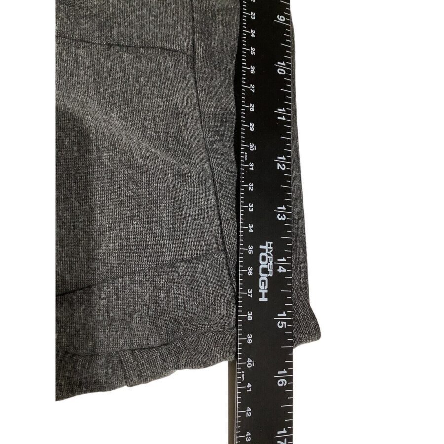 A black ruler lies vertically against a grey fabric surface. The ruler displays measurement markings in inches, indicating sizes up to 18 inches.