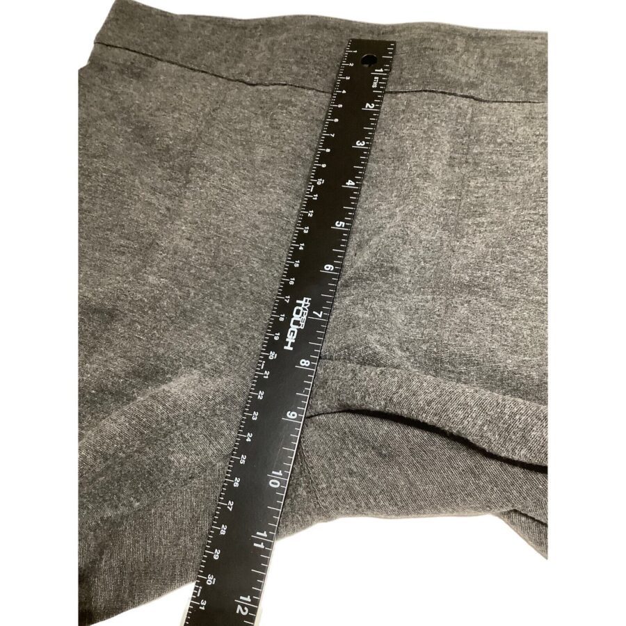 A black ruler measuring the length of gray sweatpants. The sweatpants are laid flat, and the ruler is placed diagonally across the fabric.