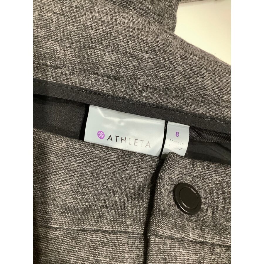 Gray Athleta garment with size 8 label displayed, featuring a black button. Fabric appears to be a textured knit material. No landmarks or buildings visible.