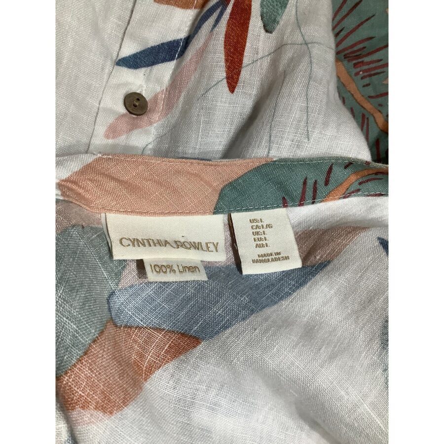 A close-up of a floral-patterned linen shirt tag, displaying the brand "Cynthia Rowley" and the material composition, 100% linen, with colorful abstract design.