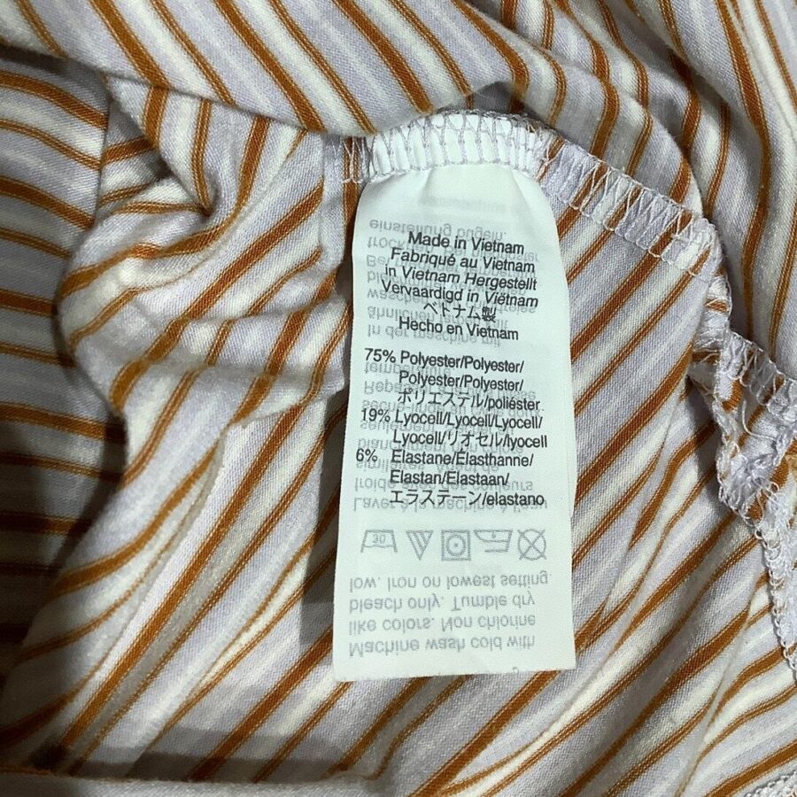 A close-up of a fabric label on a striped garment, indicating it was made in Vietnam and listing material composition and care instructions.