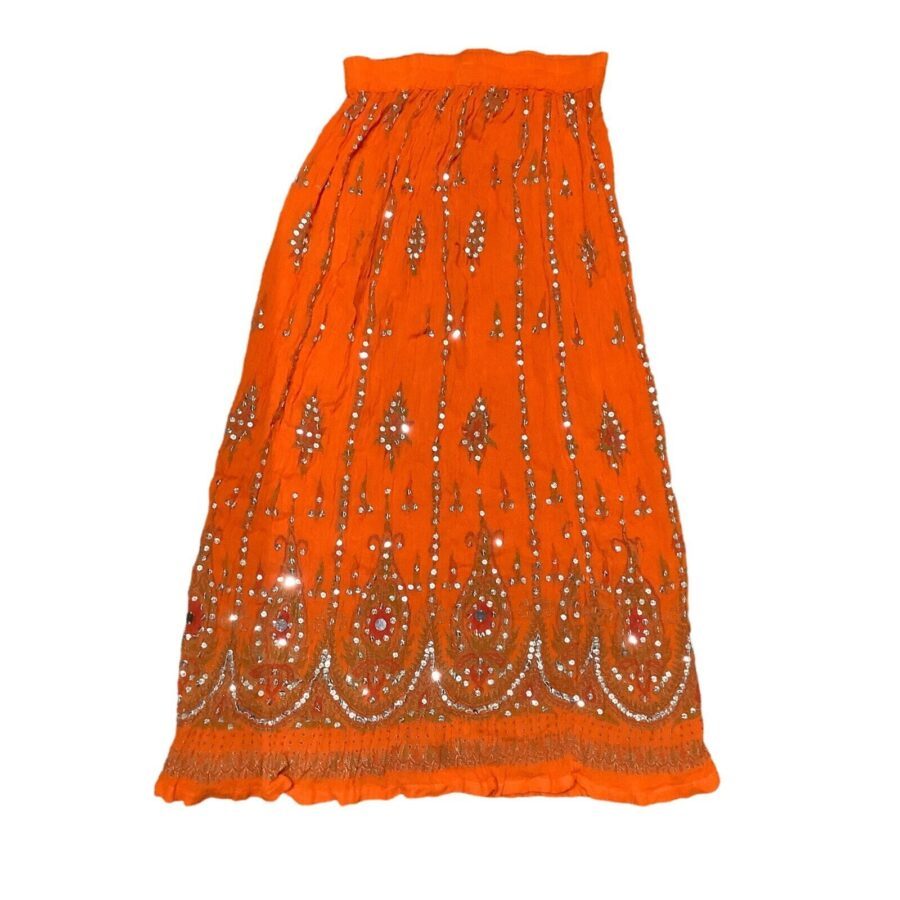 The image shows an orange embellished skirt with intricate beadwork and patterns, displayed flat against a white background. No landmarks or historical buildings present.