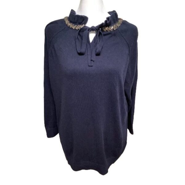 A navy blue long-sleeved blouse with embellished neckline and tie detail is displayed on a mannequin against a plain white background.