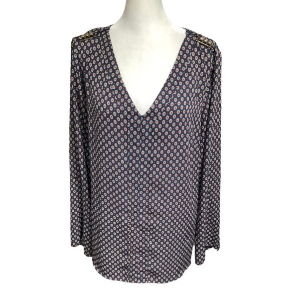 A long-sleeved blouse with a V-neckline, featuring a small geometric print pattern, is displayed on a mannequin.