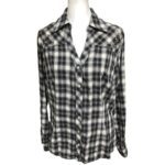 A black and white plaid long-sleeve shirt with a collar is displayed on a mannequin, featuring button-down front and decorative details on the shoulders.