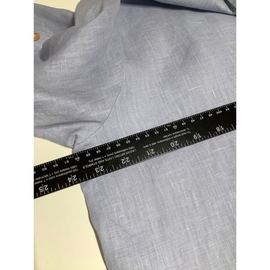 A light blue fabric with a ruler measuring 25 inches is slightly textured and neatly folded, with a visible button detail.