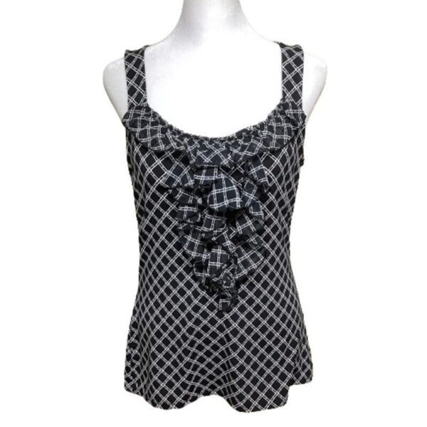 A sleeveless black-and-white plaid blouse with ruffled details is displayed on a mannequin against a plain white background.