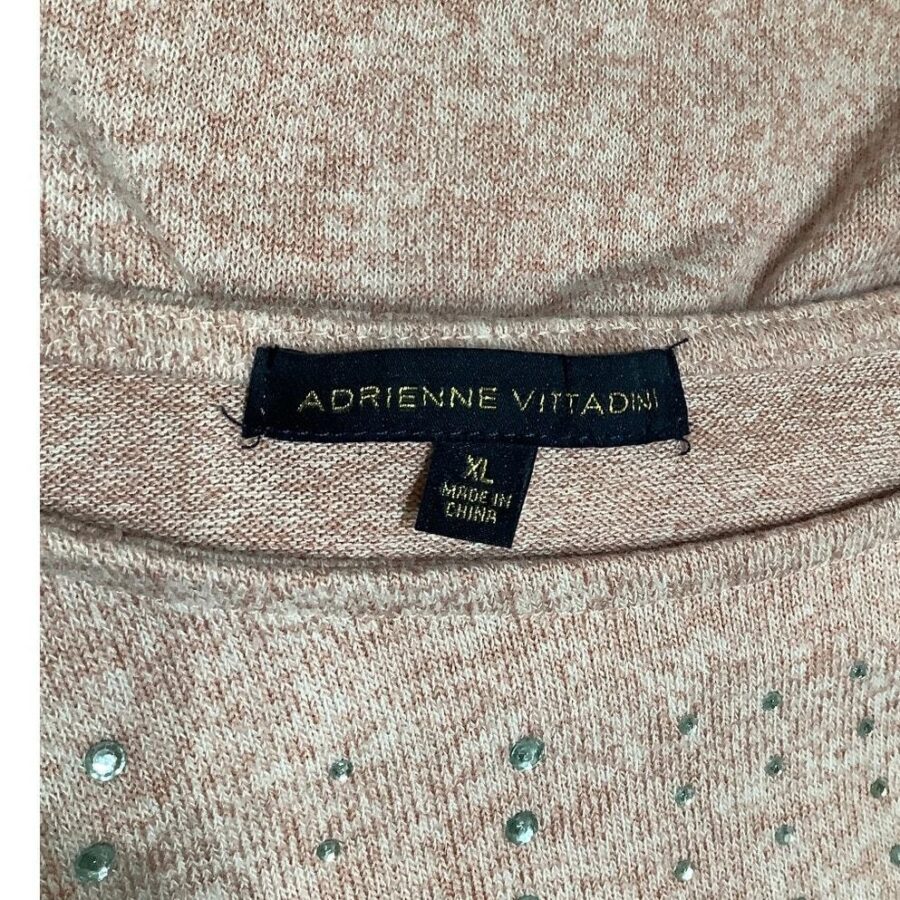 The image displays a close-up of a pink knit sweater with the "Adrienne Vittadini" label, size XL, made in China, and some decorative gems.