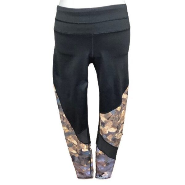 Black athletic leggings with camouflage patterns on the lower legs. The design features a high waistband and form-fitting style. No landmarks or buildings visible.