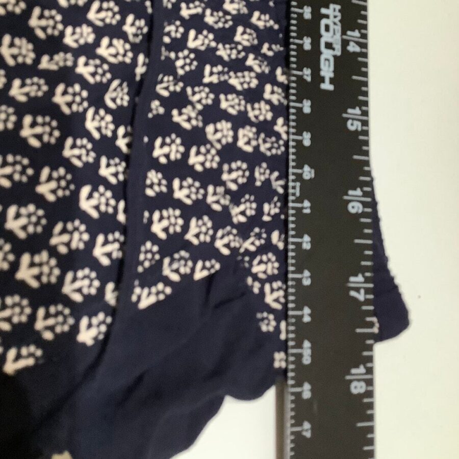 Close-up of a navy blue fabric with white floral patterns next to a black ruler showing measurements in both inches and centimeters.