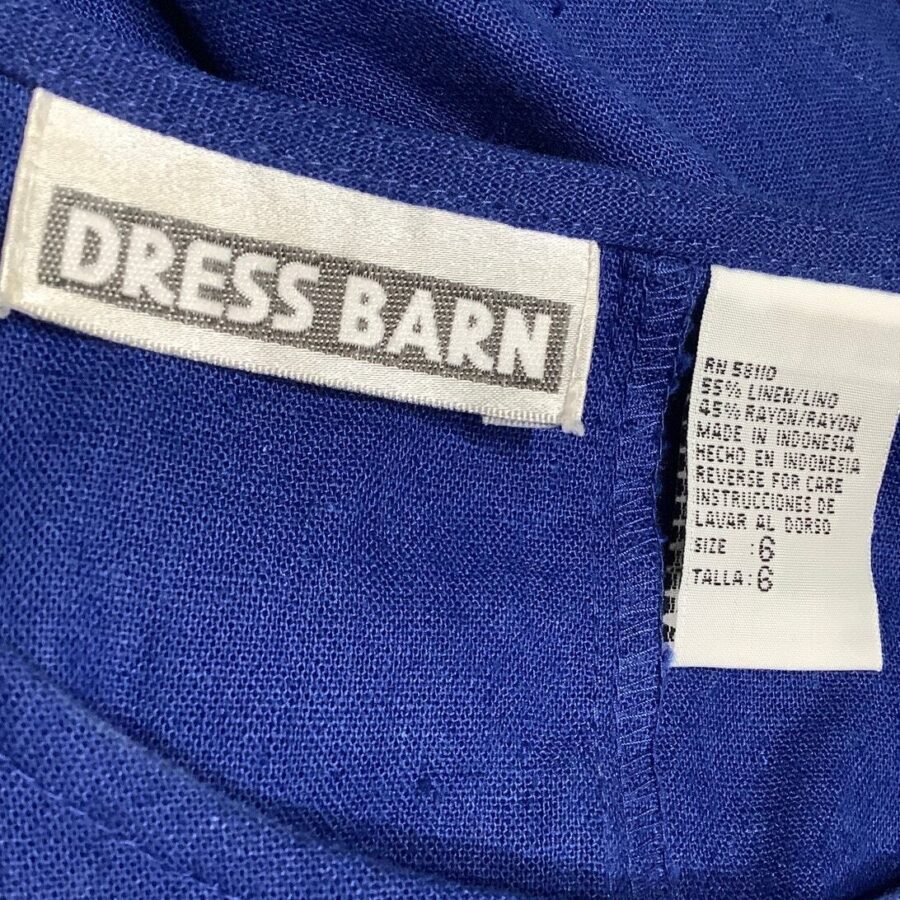 The image shows a blue garment with labels, including a "Dress Barn" brand tag and care instructions indicating the fabric composition and size.