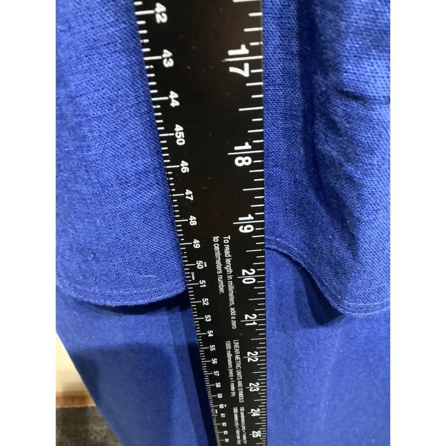 A ruler is vertically placed on a blue fabric background, displaying measurements in inches and centimeters, with numbers clearly visible up to 24 inches.