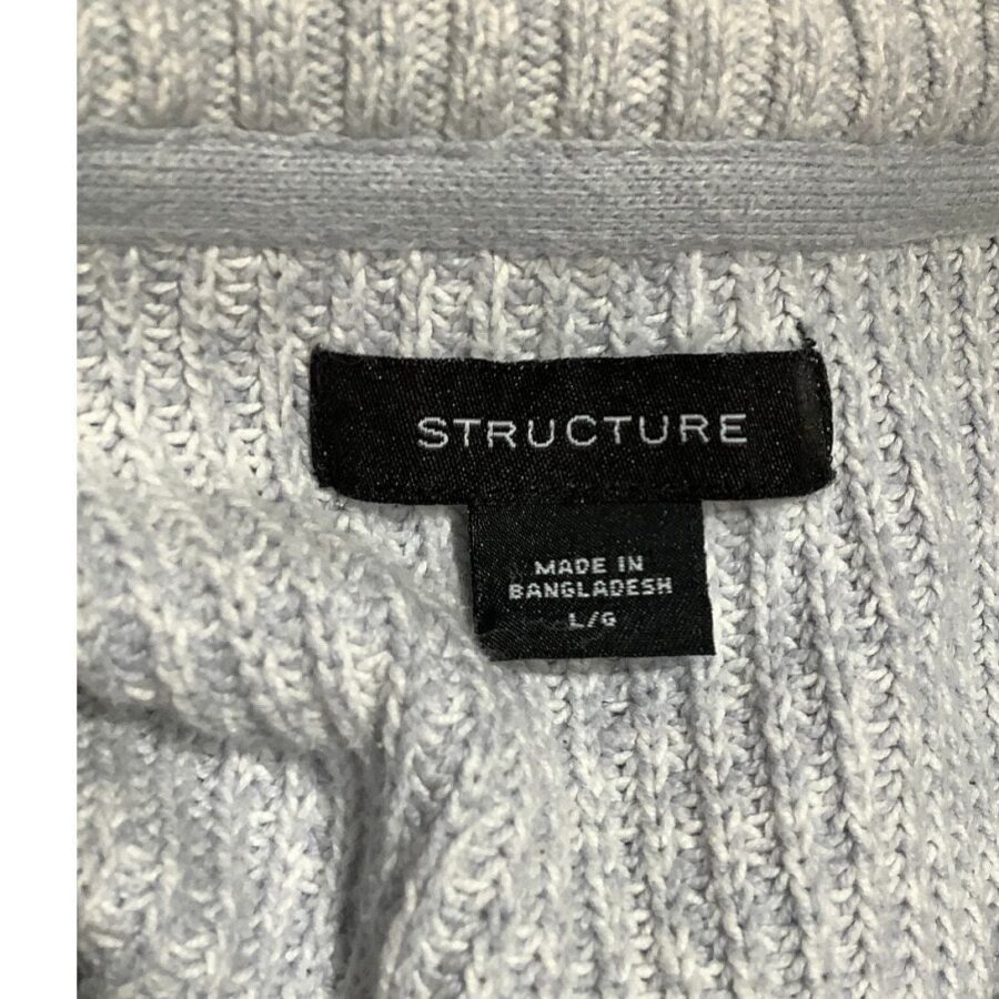 A close-up view of a gray knit garment's label reading "STRUCTURE. MADE IN BANGLADESH. L/G." The fabric exhibits a textured pattern.