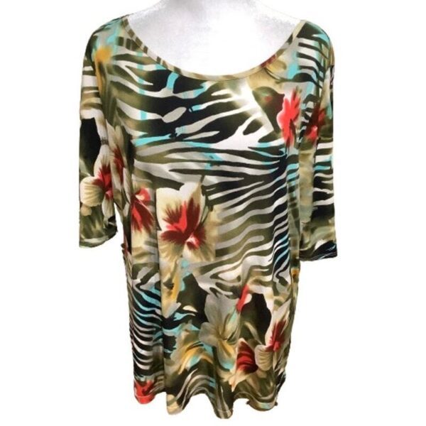 A floral-patterned blouse featuring vibrant red, white, and green hues is displayed on a headless mannequin, emphasizing its bold tropical design.