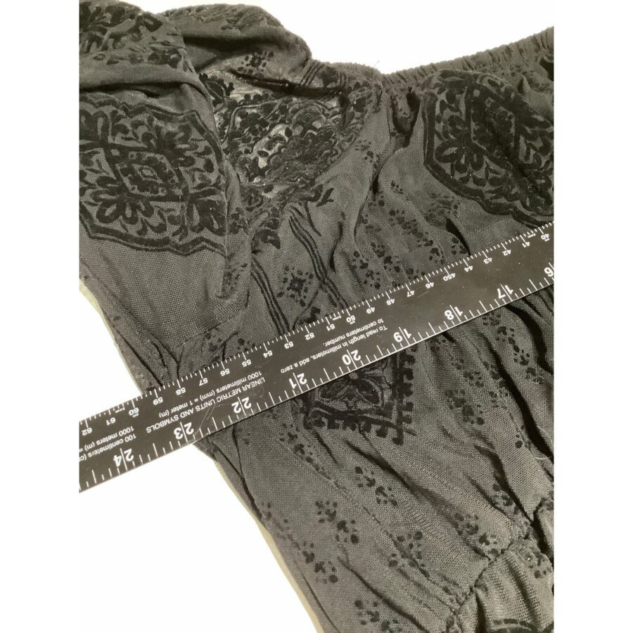 A black fabric with intricate patterns is shown, along with a measuring ruler indicating the dimensions. No recognizable landmarks or buildings are present.