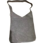 A handwoven gray crochet bag with a strap, featuring a V-shaped design at the top, lies flat against a white background.